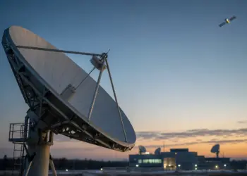 Gran antena parabólica de comunicaciones apuntando a un satélite al amanecer