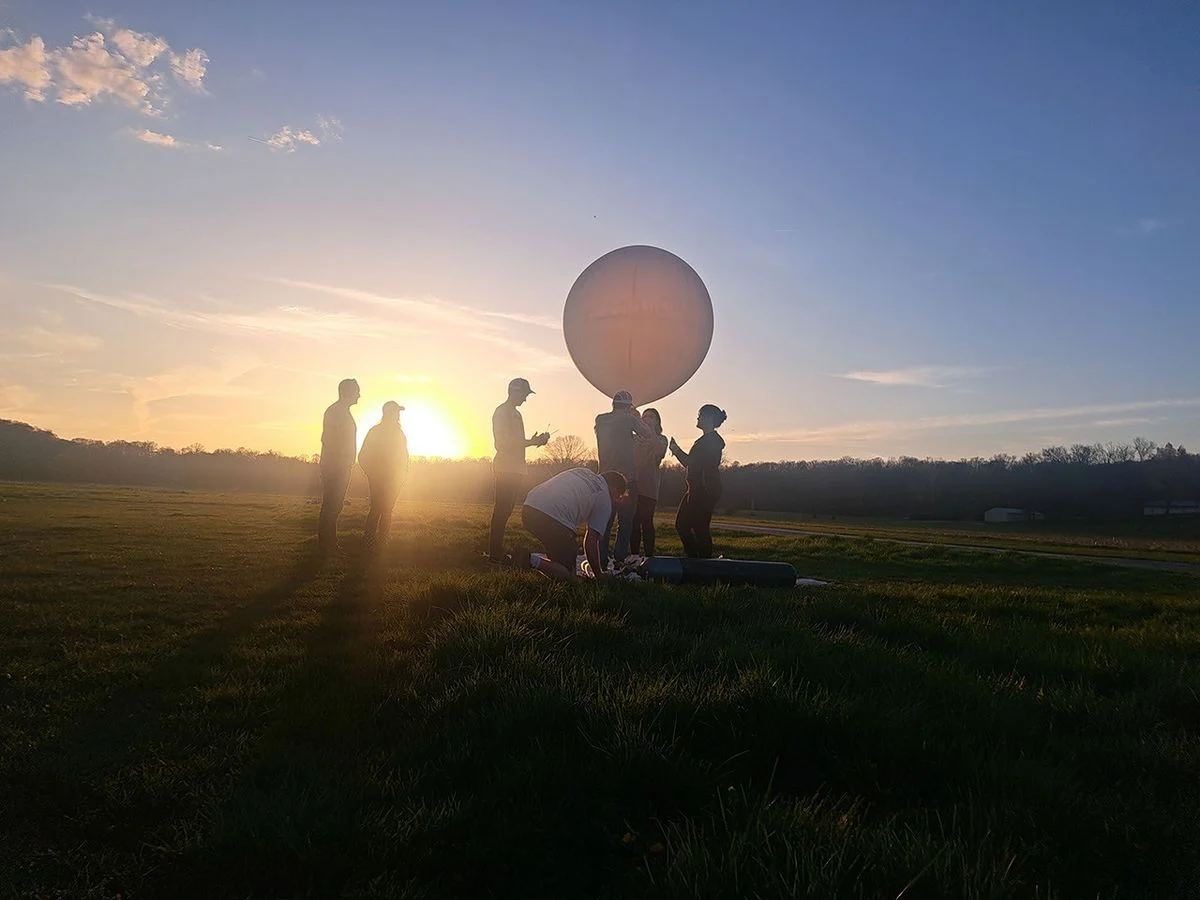 Equipo universitario prepara un globo científico al atardecer durante una campaña de eclipse