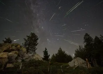 Meteoros de las Perseidas cruzan un cielo estrellado sobre un paisaje montañoso