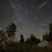 Meteoros de las Perseidas cruzan un cielo estrellado sobre un paisaje montañoso