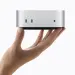 Un Mac mini plateado sostenido con una mano sobre fondo blanco