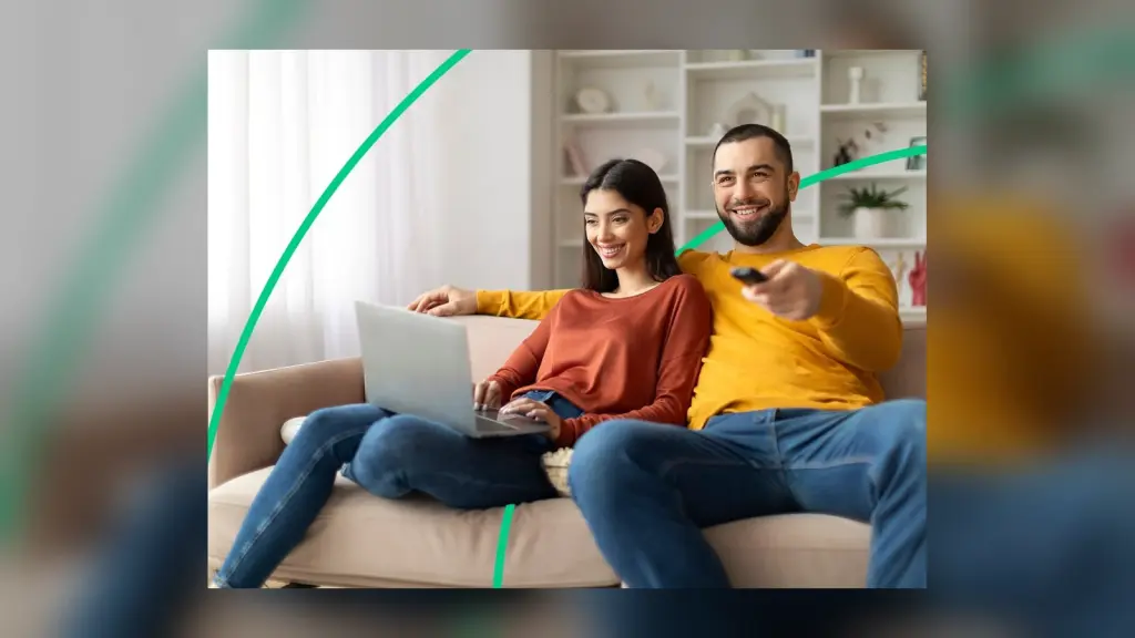 Pareja usando un portátil y televisión en casa