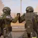 Dos Helldivers con las armaduras del Warbond Ironclad Democracy se saludan en un escenario desértico