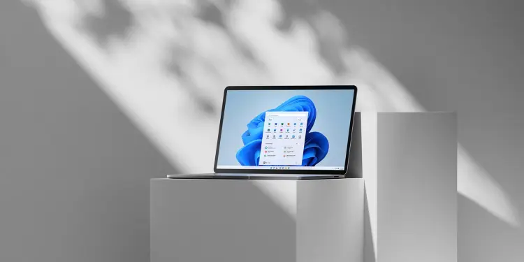 Un portátil muestra el escritorio y el menú Inicio de Windows 11