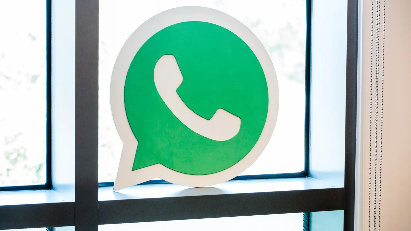 Logotipo verde de WhatsApp junto a una ventana